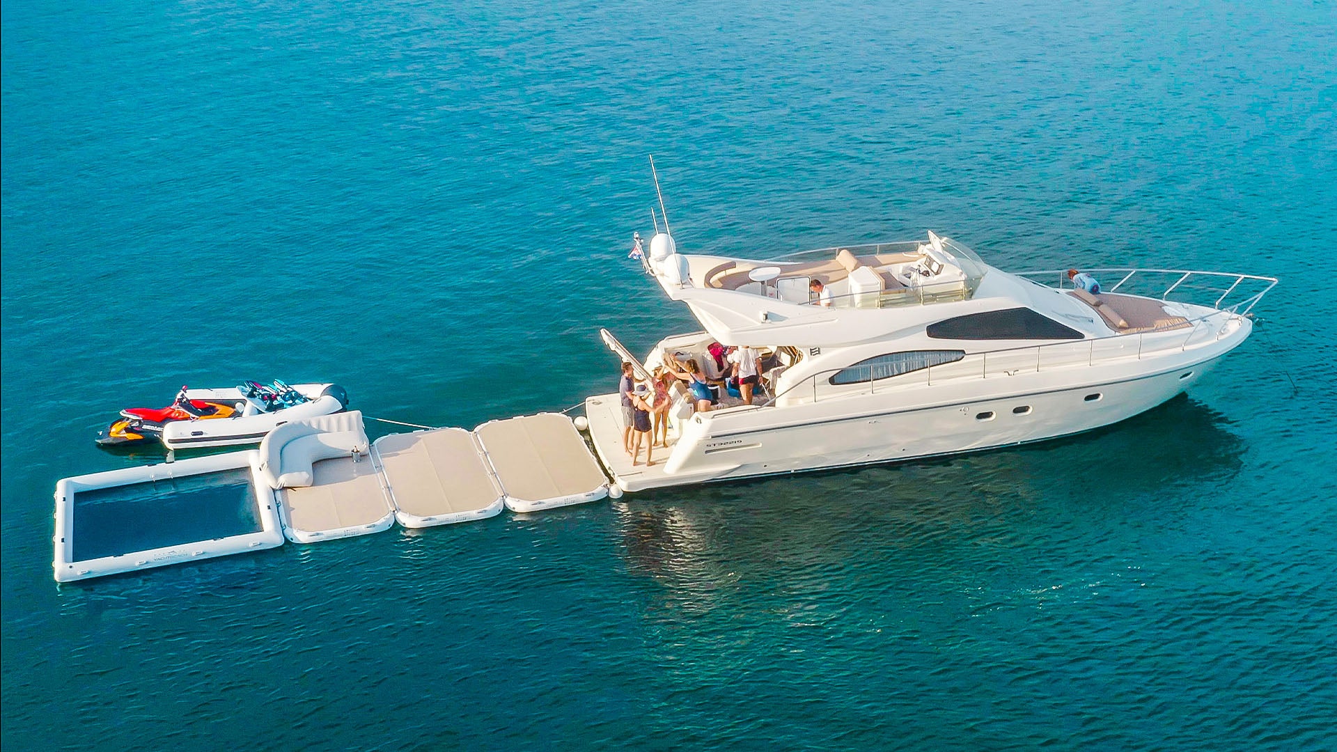 Three yacht beach platforms and a pool frame are attached to a boat on the water with people on it.