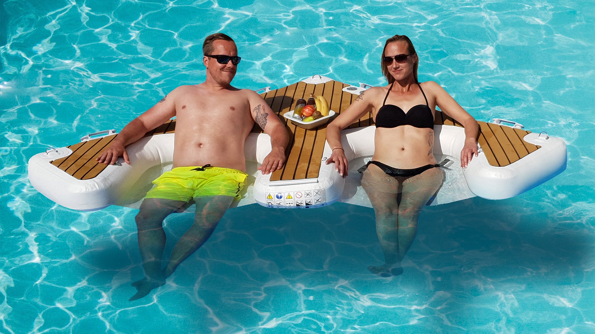 Two people sitting on the Yacht Beach Multi Dock on the water.