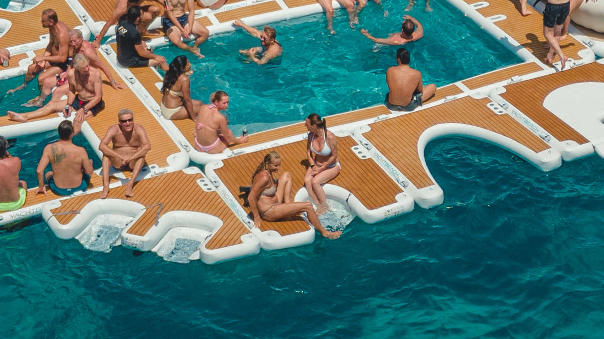 The Yacht Beach Seabob Dock is attached to other floating platforms on the water, where people sit and bathe.